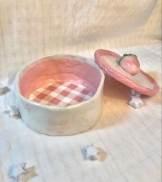 a pink bowl with a strawberry in it sitting on a white cloth covered tablecloth