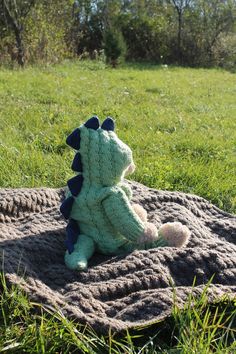 a stuffed animal sitting on top of a blanket in the middle of a grass field