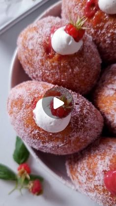 a white plate topped with powdered donuts covered in icing and strawberries