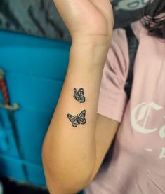 two butterflies tattoo on the left wrist and right arm, with one butterfly in the middle