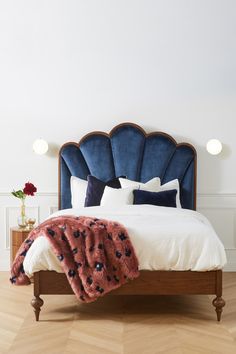 a bed with blue velvet headboard and pillows