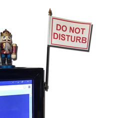 a computer monitor with a do not disturb sign on it's side and a wooden nutcracker figurine next to it