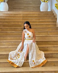 This chic, contemporary Habesha dress accentuates the modern flavor design with a hint of Ethiopian traditional wear. The slit and one-shouldered pattern gives the look a unique and daring appearance, while the hand-made tilf showcases the cultural touch. It's prefect for weddings, anniversaries, birthdays, graduation or any event planned. Estimated delivery : 1 week to 2 weeks Contact WhatsApp +1(304)-306-2784Email: contact@ethiopian.store Ethiopian Fabric, Holiday Wedding Dress, Habesha Dress, Ethiopian Dress, Habesha Kemis, Traditional Wear, Caicos Islands, Wedding Dresses Simple, Turks And Caicos Islands