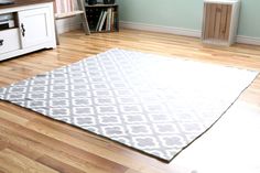 a living room with hard wood flooring and a white rug on the wooden floor