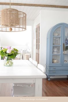 a dining room table and chairs with flowers in a vase on the center island, next to a china cabinet