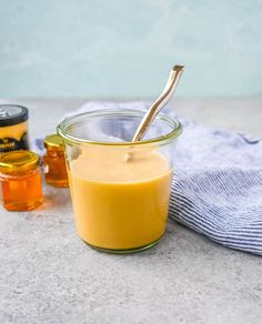 a glass jar filled with liquid next to honey and a blue towel on a table