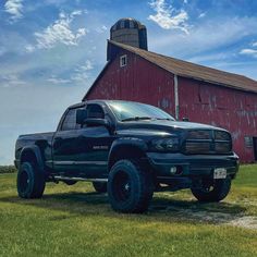 a black truck parked in front of a red barn