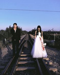 a bride and groom standing on train tracks