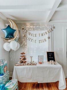 a white table topped with lots of balloons next to a window covered in stars and confetti