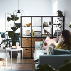 a woman sitting on top of a couch next to a plant in a living room