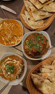 several bowls of food on a table with utensils