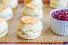 biscuits and cranberry sauce sitting on a baking sheet next to some bread rolls