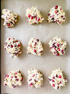 twelve cookies with cranberries and white chocolate chips on a baking sheet, ready to be baked