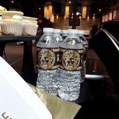 three water bottles sitting on top of a table next to cupcakes and muffins