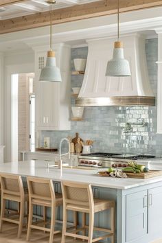 a kitchen with white cabinets and blue countertops is pictured in this image, there are four stools at the center of the island