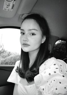 a woman sitting in the back seat of a car with her eyes closed and looking at the camera