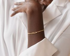 a woman wearing a gold bracelet with the word allure on it's wrist