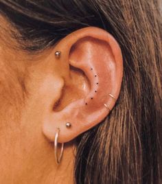 a woman's ear with small black dots on the middle part of her left ear