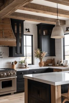 a kitchen with black cabinets and an island in front of a stove top oven next to a window