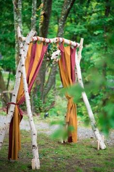 an outdoor wedding ceremony with white birch trees and orange draping on the side