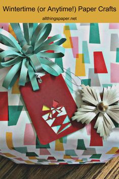 an origami gift bag with paper flowers on it and the words wintertime or anytime paper crafts