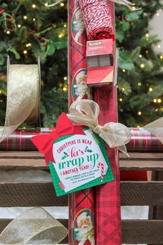 christmas presents wrapped in red and green paper are stacked on top of each other near a christmas tree