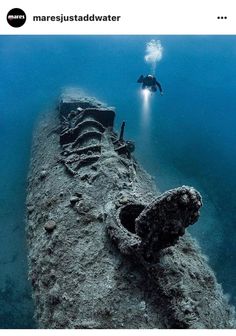 an underwater view of a sunken ship in the ocean with a scuba diver looking at it