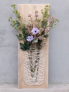 a vase filled with flowers sitting on top of a wooden shelf next to a wall