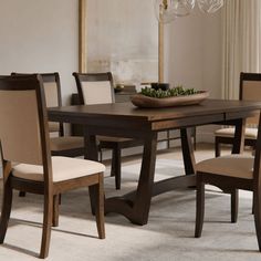 a dining room table with chairs and a bowl of fruit on top of the table