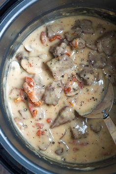 a pot filled with meat and gravy on top of a wooden table