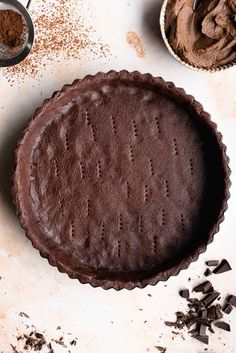 a chocolate pie sitting on top of a table next to bowls of chocolate shavings