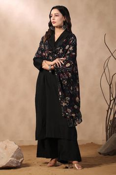 Black A-line kurta with pleated neckline. Comes with cotton silk pant and floral printed dupatta.
Components: 3
Pattern: Printed
Type Of Work: Floral
Neckline: V Neck
Sleeve Type: Three Quarter
Fabric: Cotton Silk
Color: Black
Other Details: 
Attached lining
Approximate product weight: 0.5-1 kg
Occasion: Work - Aza Fashions Semi-stitched Black Cotton Silk Blouse Piece, Unstitched Black Blouse Piece, Black Anarkali Chanderi Palazzo Set, Black Palazzo Set With Straight Kurta, Black Palazzo Set With Sheer Dupatta For Eid, Black Anarkali Palazzo Set In Georgette, Black Chanderi Palazzo Set With Dupatta, Black Palazzo Set With Straight Kurta And Dupatta, Black Chanderi Palazzo Set For Eid