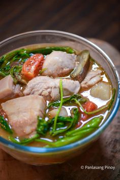 a bowl filled with meat and vegetables on top of a wooden table