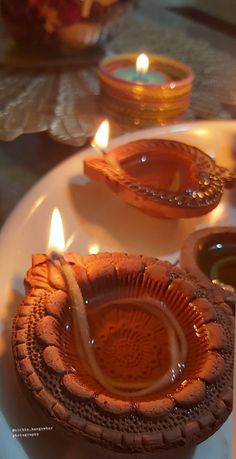 candles are lit on a plate with decorative designs