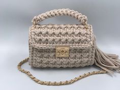 a crocheted purse with a tasselled handle and gold hardware on the front