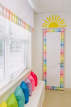 colorful pillows are lined up in front of a white door with the sun painted on it