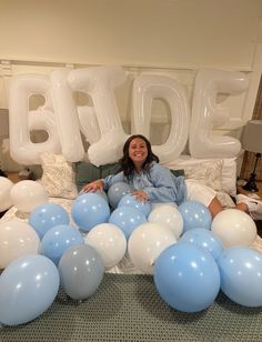 a woman laying on a bed surrounded by blue and white balloons that spell out the word bride