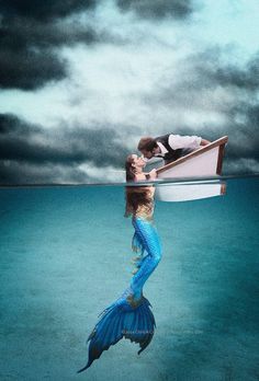 a man and woman are kissing on a boat floating in the ocean under cloudy skies