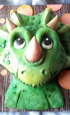 there is a cake made to look like a green monster with big eyes and horns