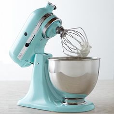 a blue mixer with a whisk in it's bowl on a table