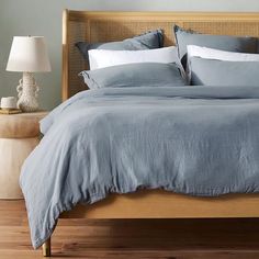 a bed with blue linens and pillows on top of it next to a night stand