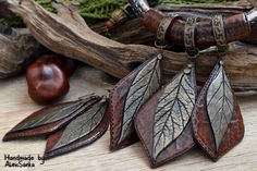 three leaf shaped pendants are hanging from a tree branch