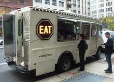 two people standing in front of an eat truck