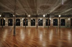 an empty room with wooden floors and exposed ceiling lights in the center is lit by recessed light bulbs