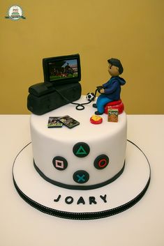 a cake with a man sitting on top of it, holding a video game controller