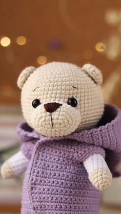 a crocheted teddy bear wearing a purple sweater