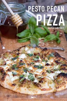 a pizza sitting on top of a wooden cutting board next to a jar of honey