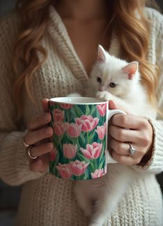 a woman holding a coffee cup with a cat in it