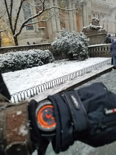 a person holding an object in their hand while standing on snow covered ground next to trees