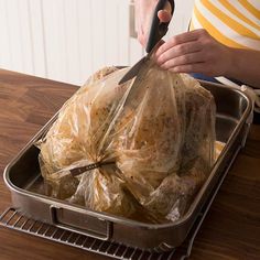 a person holding a plastic bag filled with food on top of a metal tray next to scissors